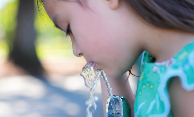 young girl using drinking fountain